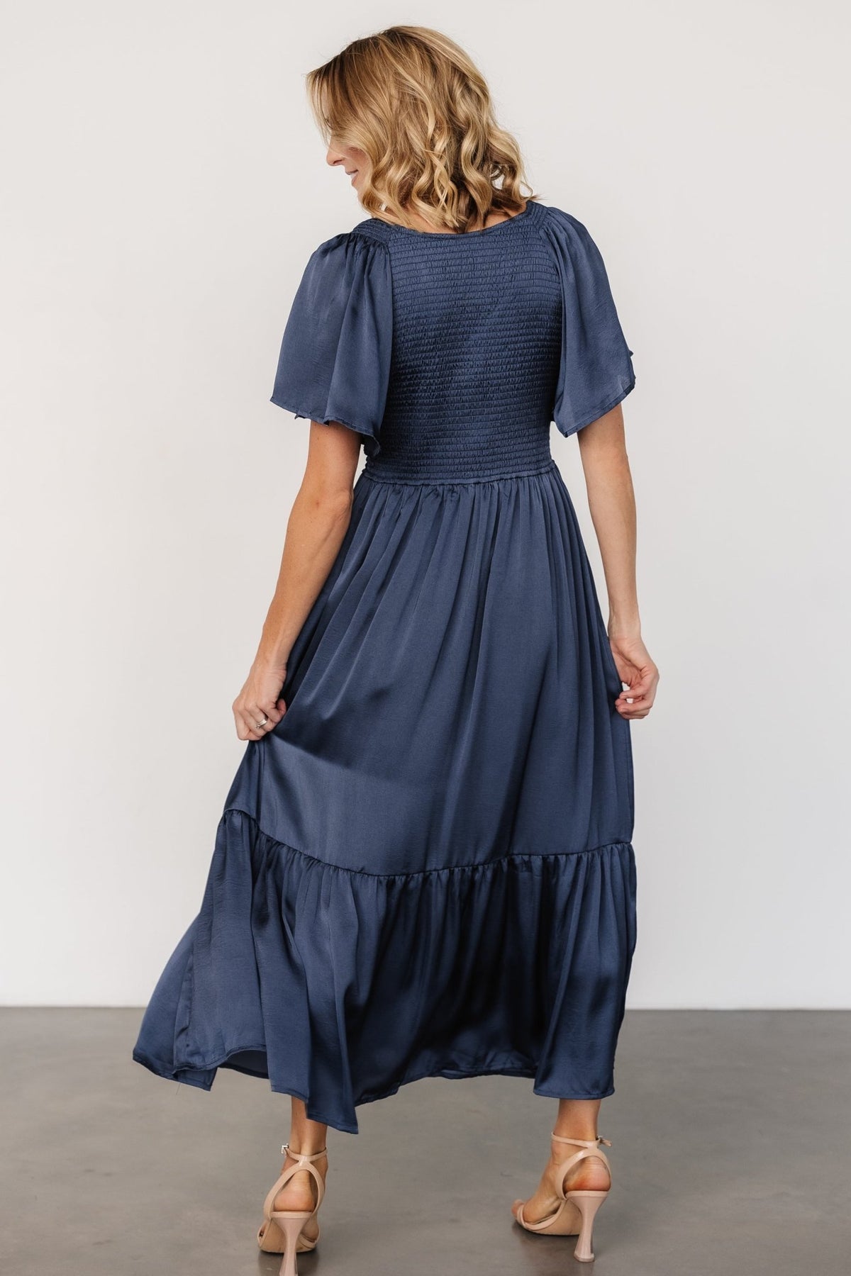 Detail shot of satin-like polyester fabric showing subtle sheen and soft drape of the Lovell smocked midi dress.
