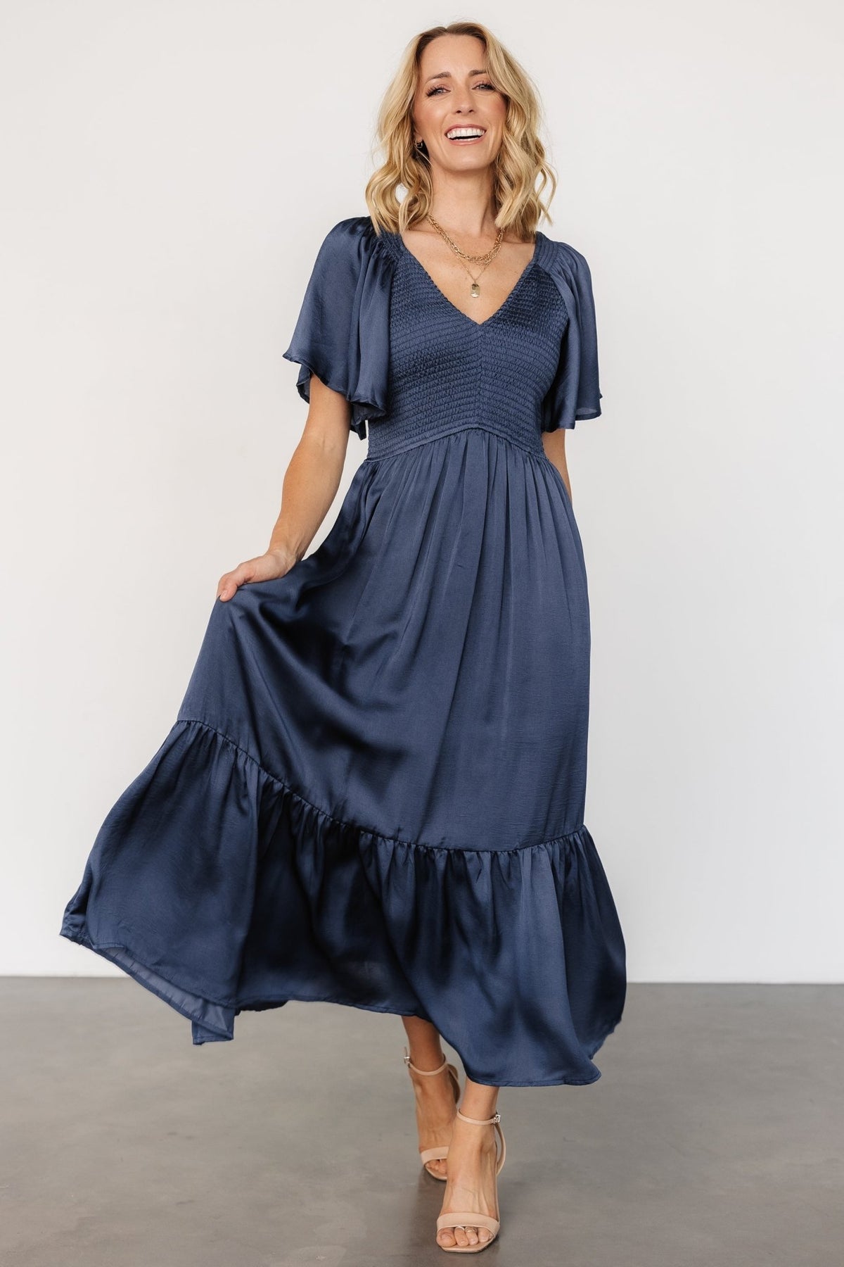 Front model view of Lovell Smocked Midi Dress in midnight blue showing rounded V neckline and smocked bodice.