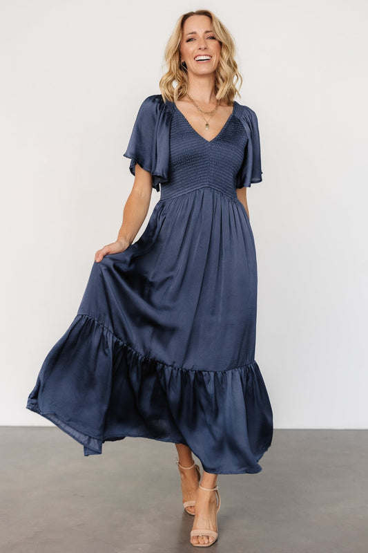 Front model view of Lovell Smocked Midi Dress in midnight blue showing rounded V neckline and smocked bodice.