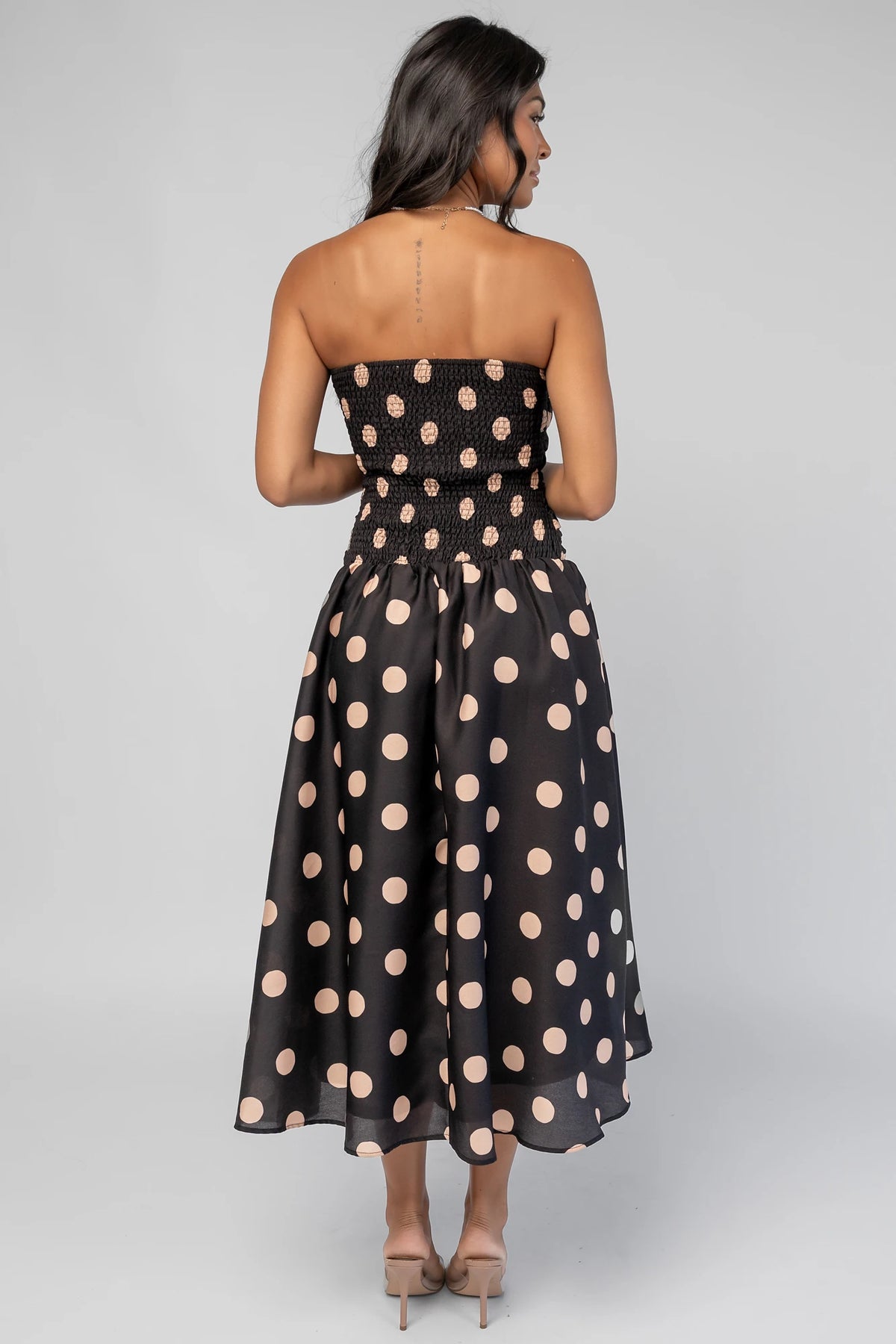 Lucienne Strapless Midi Dress in Black + Beige Dot with strapless neckline, cinched bodice, smocked back, and dropped waist.