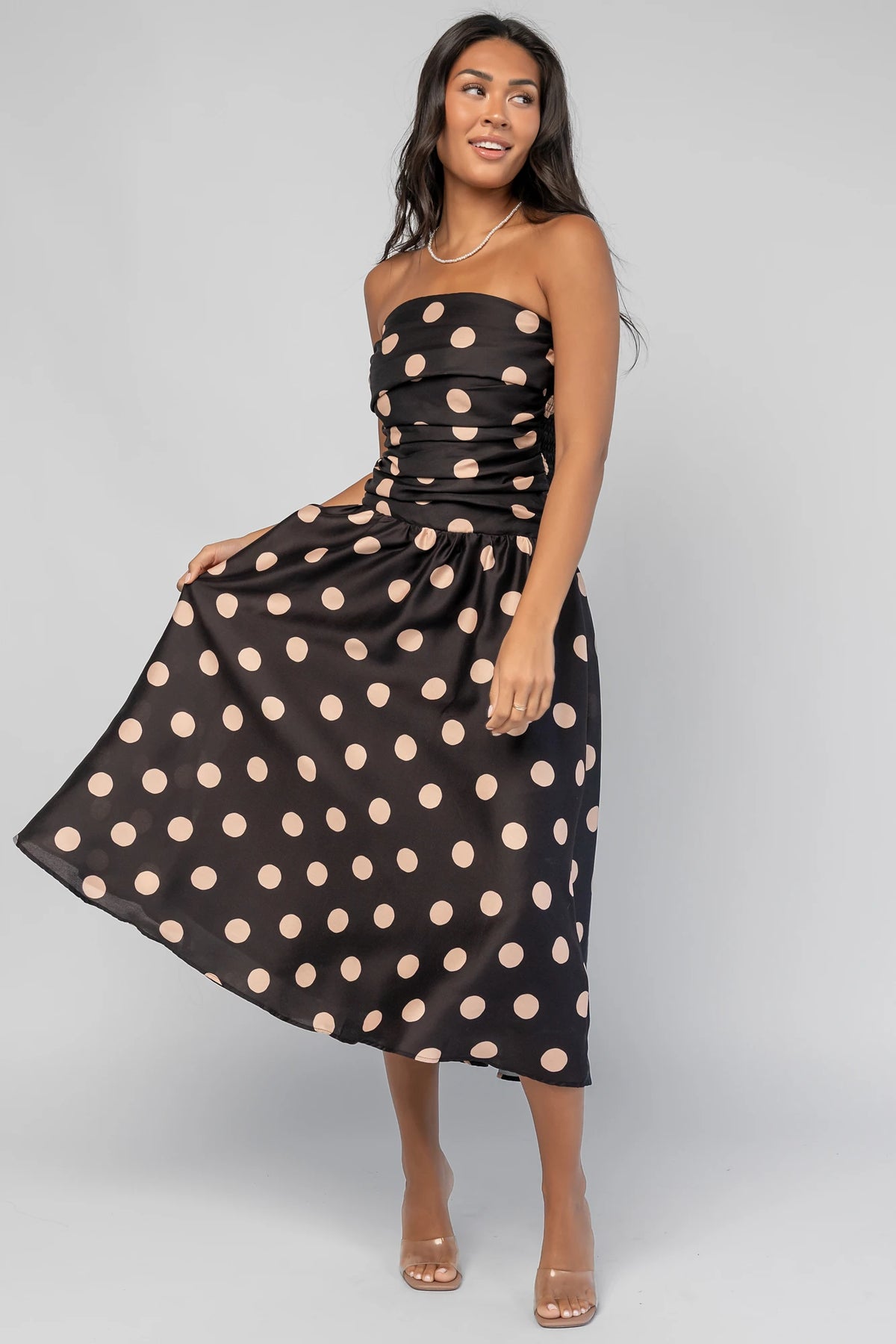 Lucienne Strapless Midi Dress in Black + Beige Dot with strapless neckline, cinched bodice, smocked back, and dropped waist.