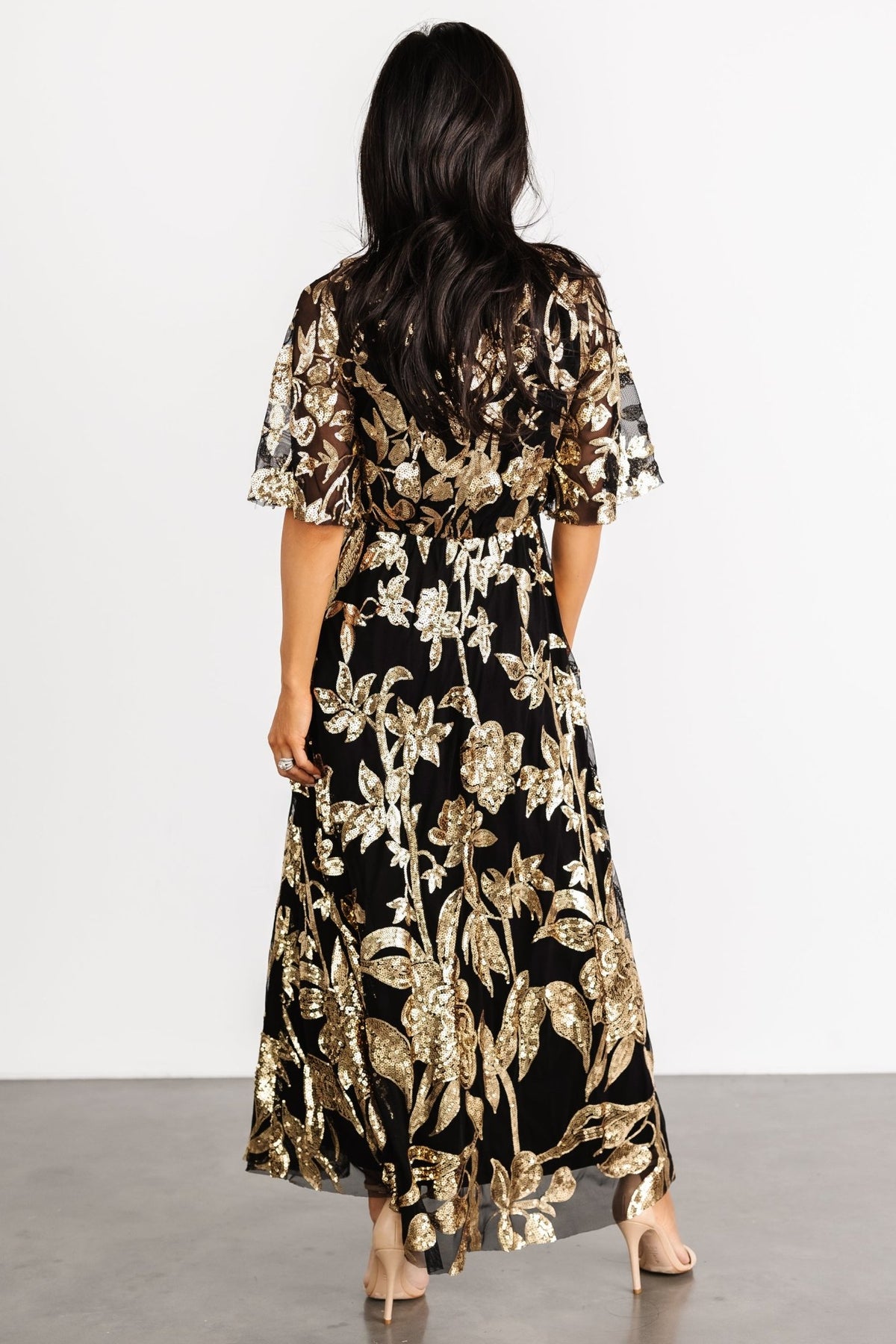 Close-up detail of gold sequin floral embroidery on black tulle overlay, showing texture and delicate sequin placement.