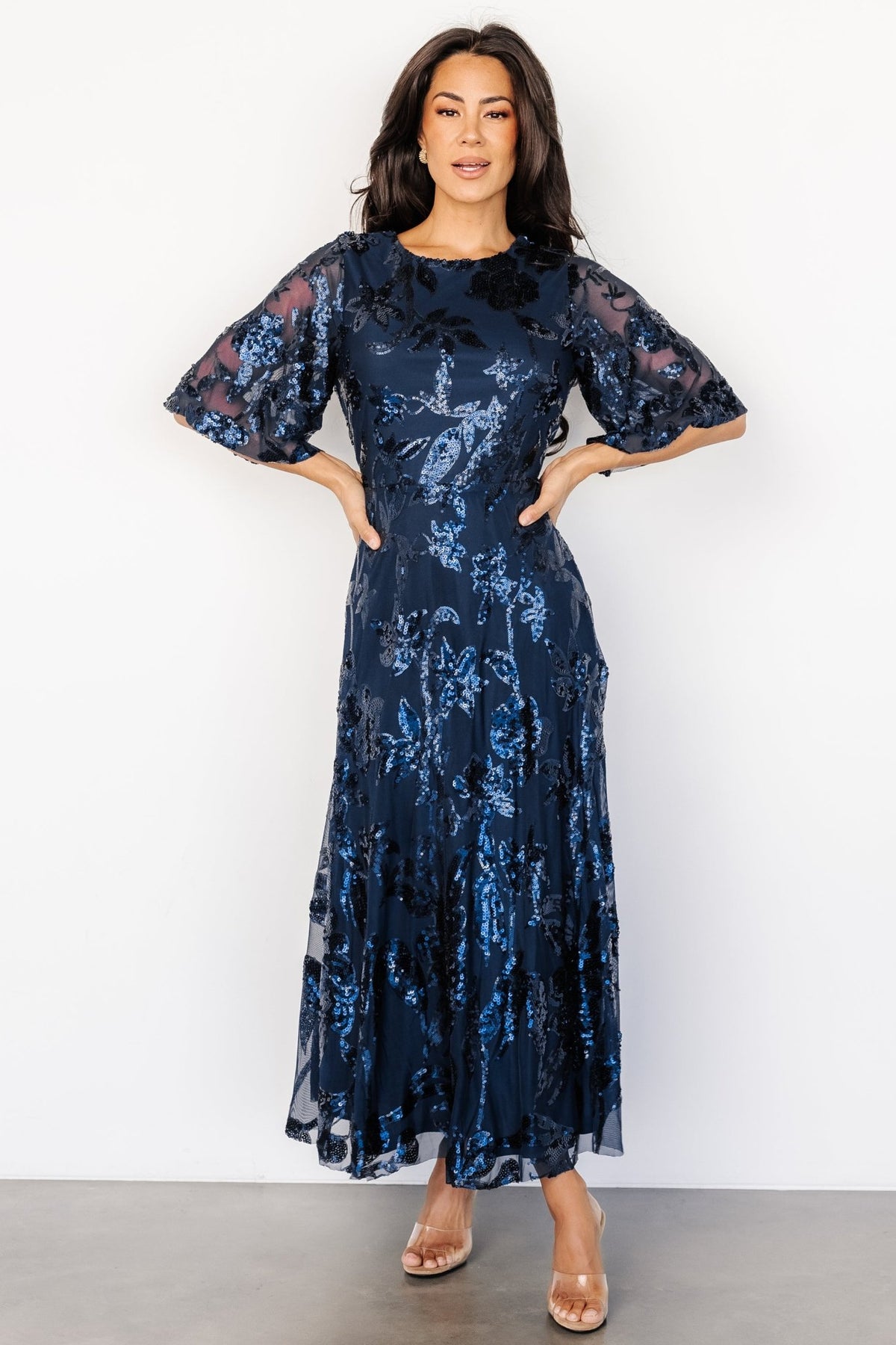 Front view of navy tulle maxi dress with monochromatic floral sequin pattern, round neckline, and flowing raw-hem skirt (full-length).