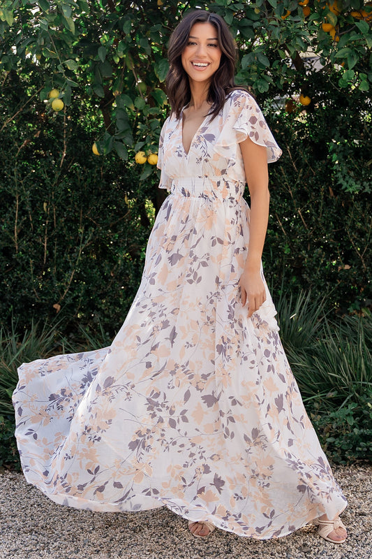 Off-white printed chiffon maxi dress with metallic floral shimmer, V-neckline, short flutter sleeves, and smocked waist; studio front view on model.
