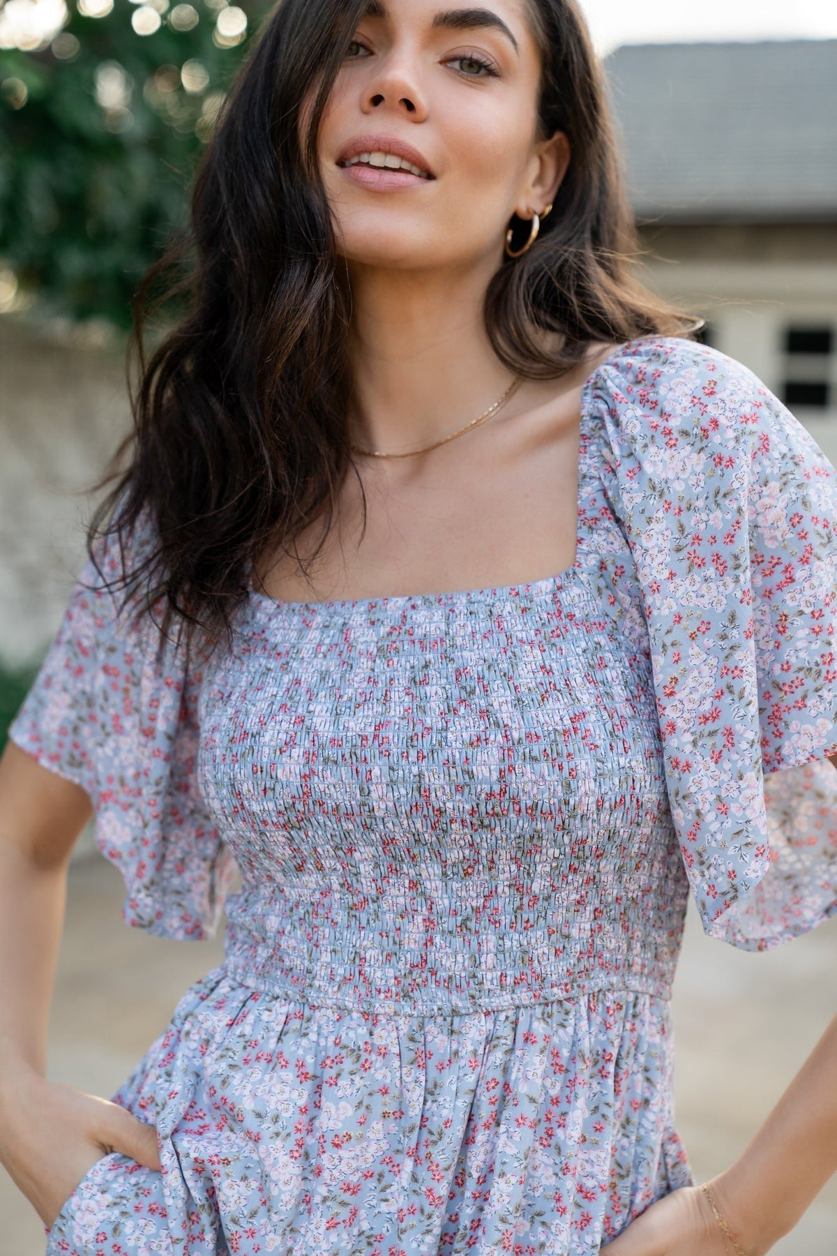 Back view of Lyssa midi dress in dusty blue floral print showing square back and the gentle tiered silhouette at the hem.