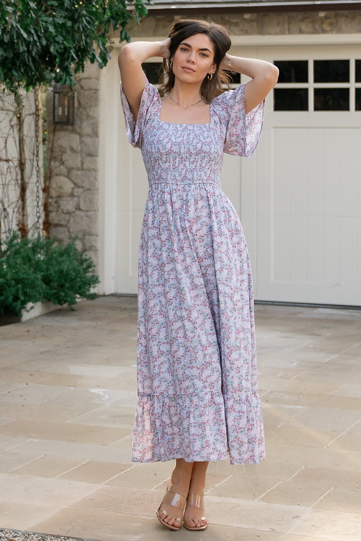 Front view of Lyssa smocked midi dress in dusty blue floral print on model, showing square neckline, short flutter sleeves, and hidden side pockets.