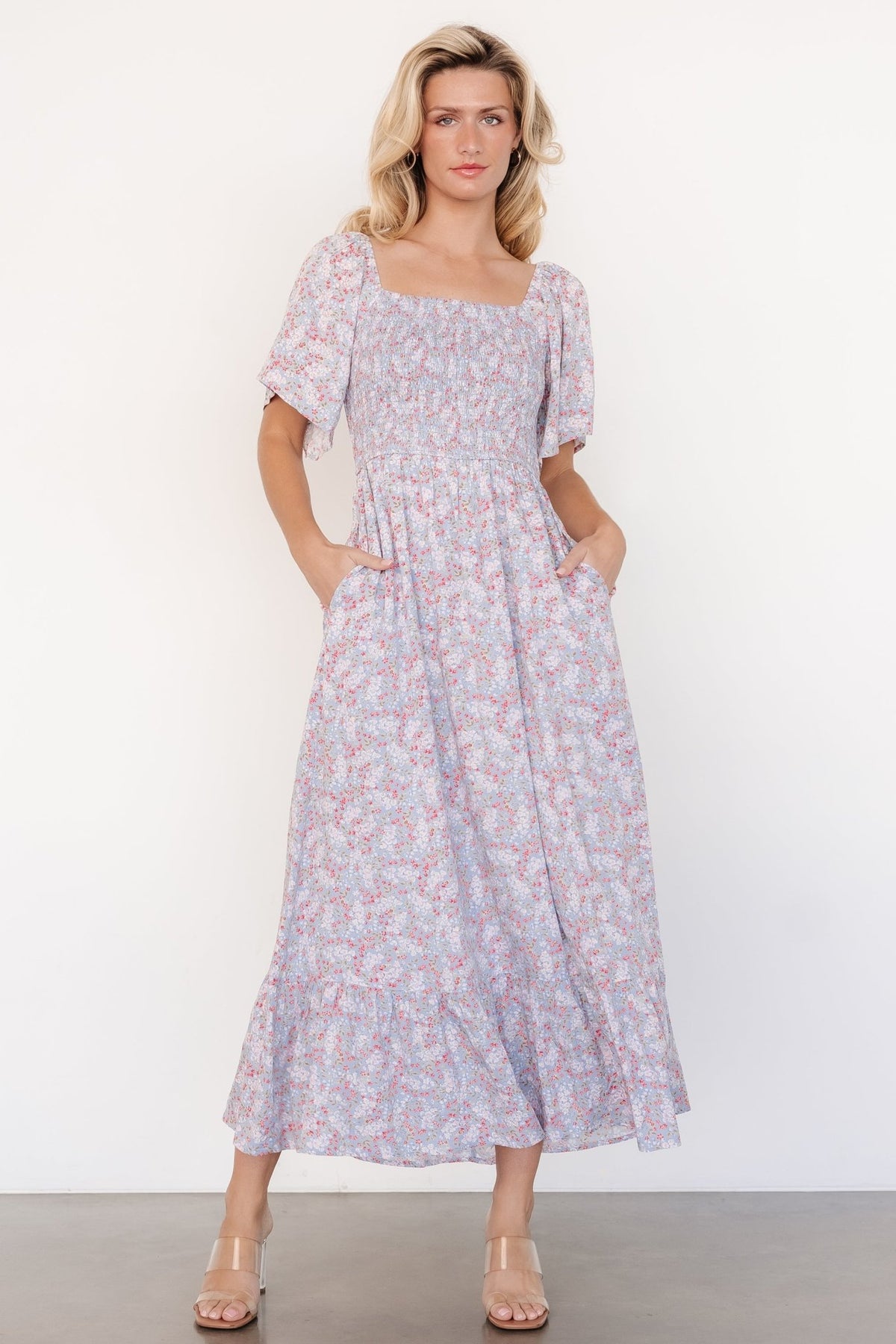 Three-quarter view highlighting elastic waistline and single-tier midi skirt of the Lyssa smocked dress in dusty blue floral; lined to the last tier for smooth drape.