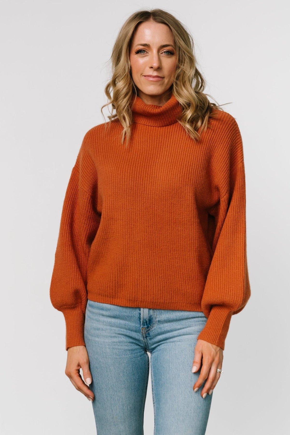 Front view of spice-colored ribbed turtleneck sweater with relaxed body and long bubble sleeves; 70% acrylic, 30% nylon knit, casual fit.