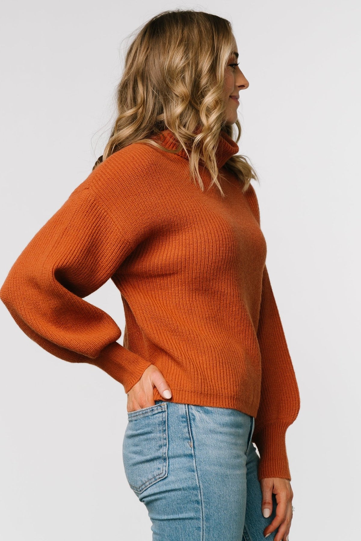 Model portrait in spice ribbed turtleneck sweater showing neckline height, relaxed fit, and casual fall styling.