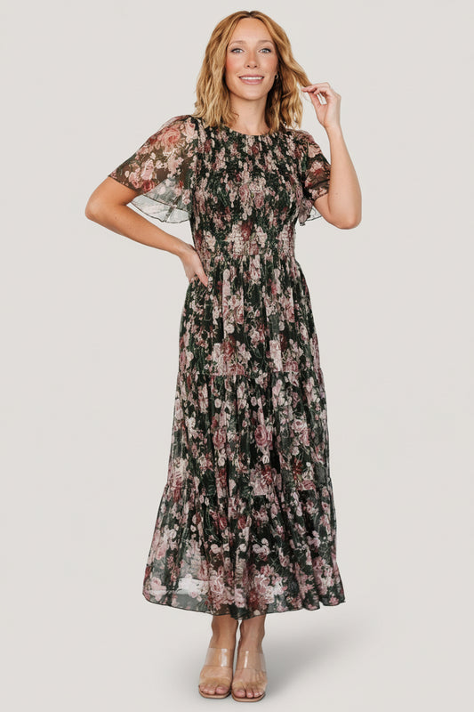 Front view of dark green embroidered tulle midi dress with blush and berry florals, showing smocked bodice and flutter sleeves.