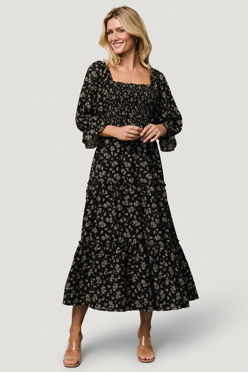 Front view of Margareta Tiered Midi Dress in black floral print on model, showing Florentine neckline and smocked bodice with tiered skirt.