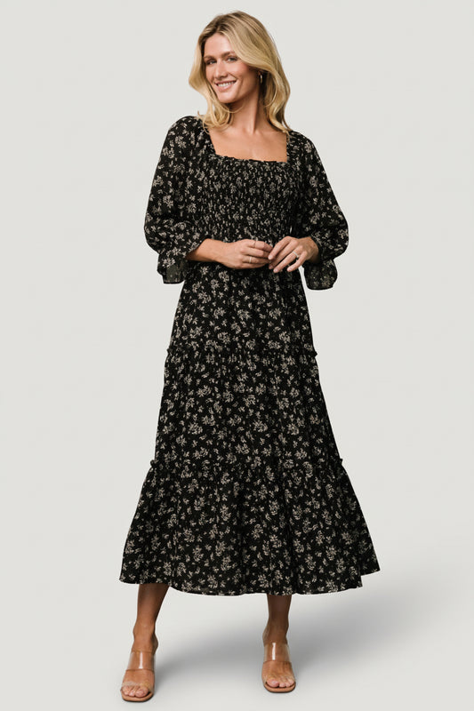 Front view of Margareta Tiered Midi Dress in black floral print on model, showing Florentine neckline and smocked bodice with tiered skirt.