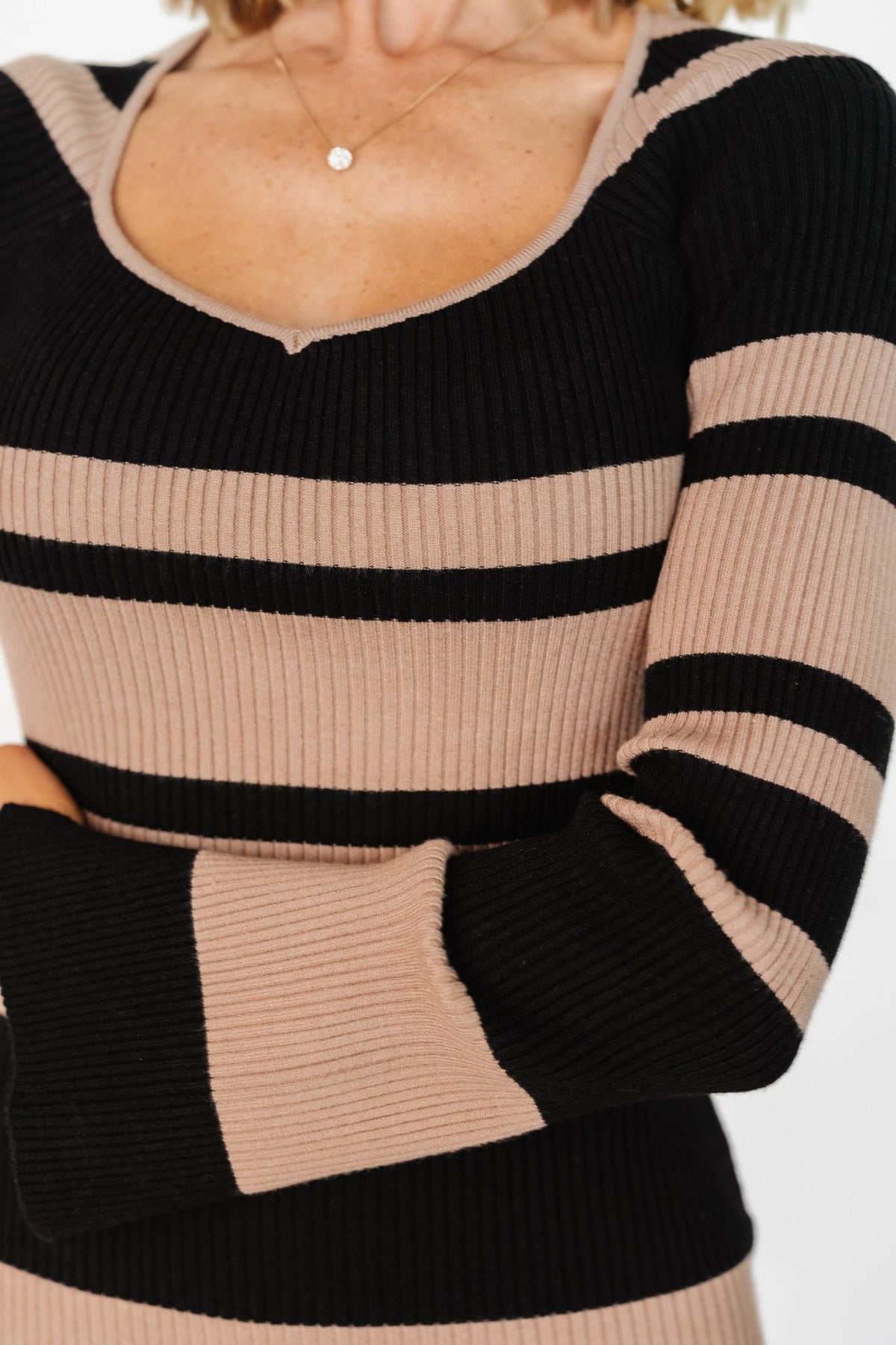 Three-quarter view of Marika midi dress showing side seam and striped pattern, ribbed knit texture and knee-high center-back slit for movement.