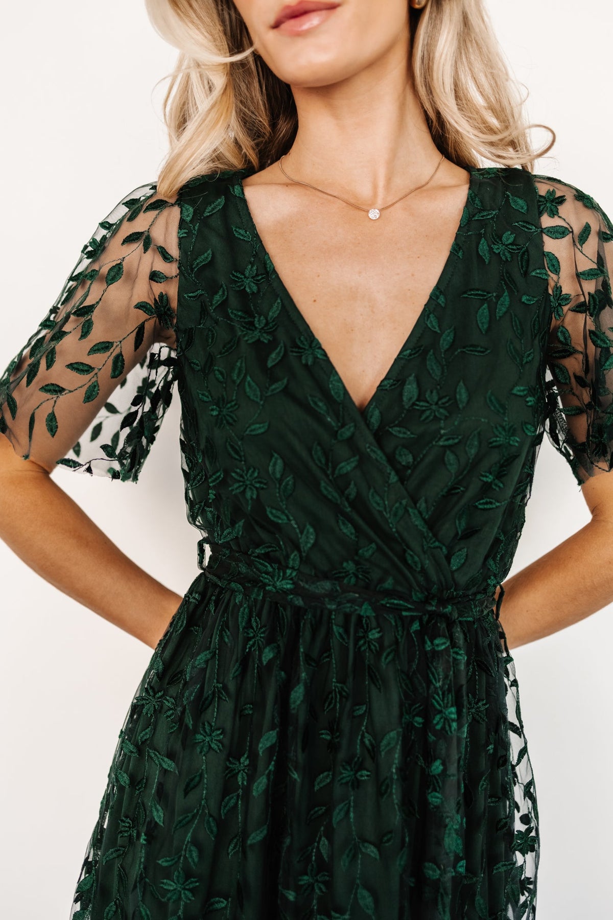 Back view of the maxi dress showing inverted lining seam construction, clean raw-cut hem, and vine-embossed organza texture across the skirt.