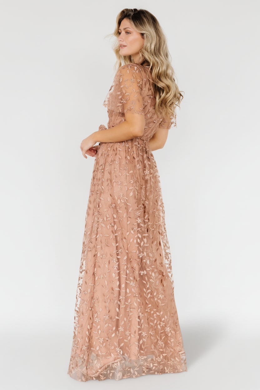 Back view of nude-rose vine-embossed organza maxi dress, showing inverted lining seam and raw-cut hemline detail.