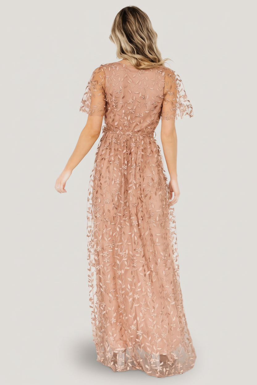 Close-up of vine embossing and fabric texture on the organza of a nude-rose maxi dress, highlighting floral pattern detail.