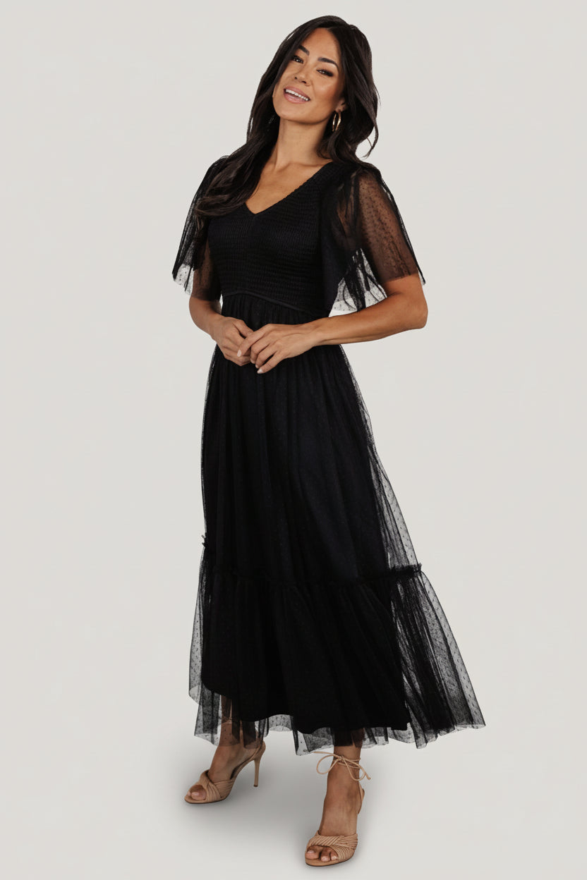 Front view of black smocked tulle midi dress with elastic V-neck, smocked bodice and a single tiered ruffle skirt, shown on a model.