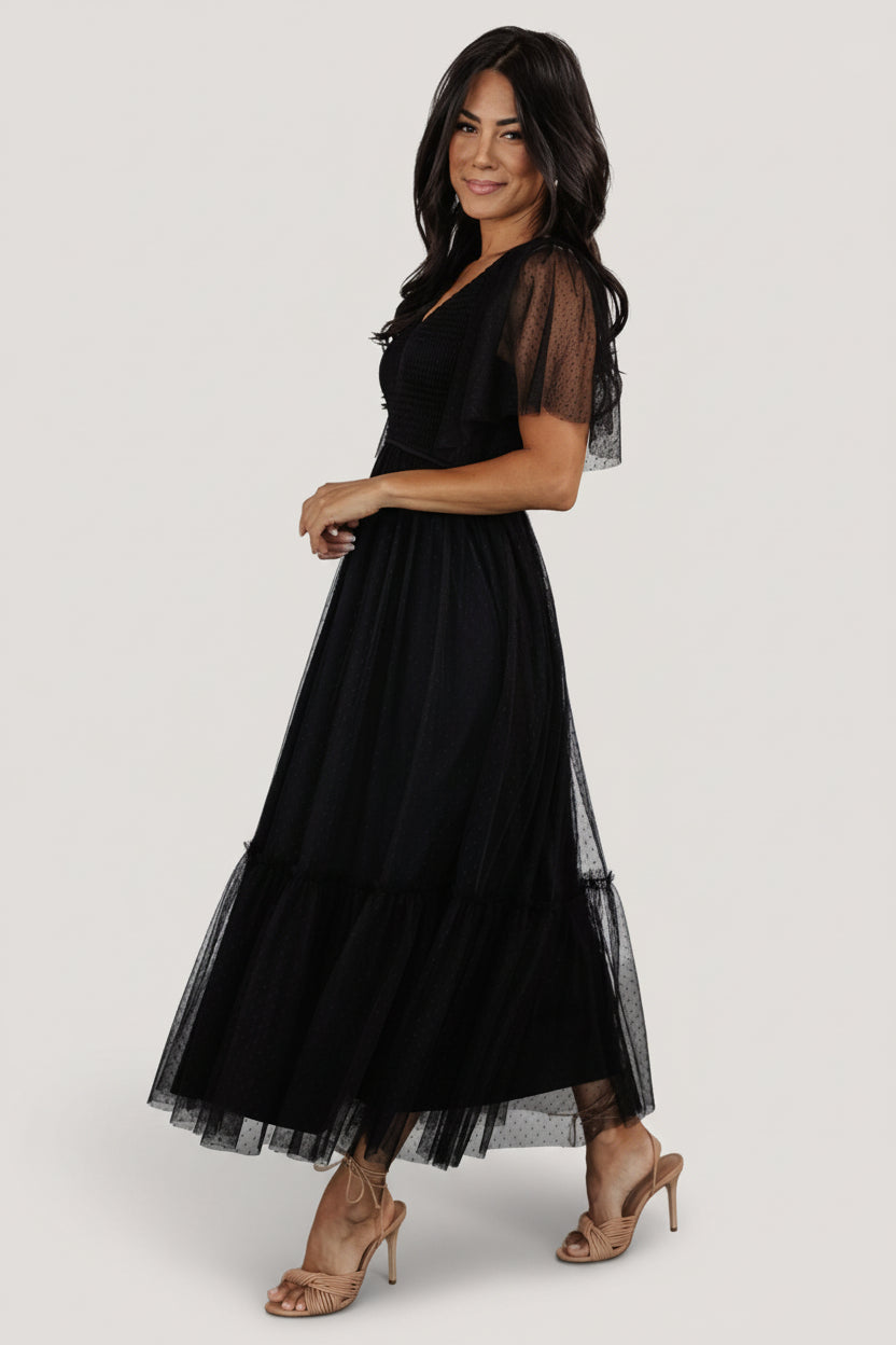 Side view of black tulle midi dress highlighting elastic V-neck, flirty short sleeves and the gentle gather of the tiered skirt silhouette.