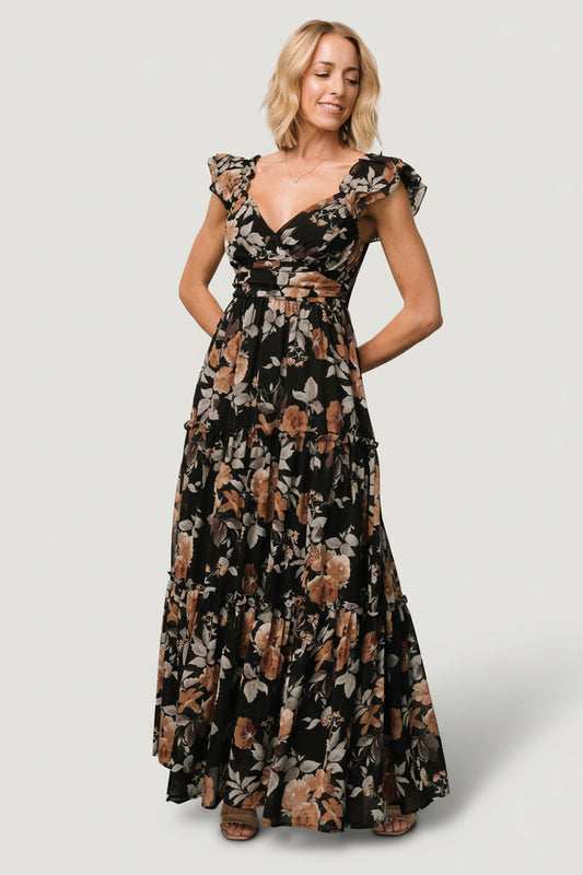 Front view of Martina Maxi Dress in black with muted copper florals, showing wide V‑neckline, gathered bust, and flutter sleeves on model.