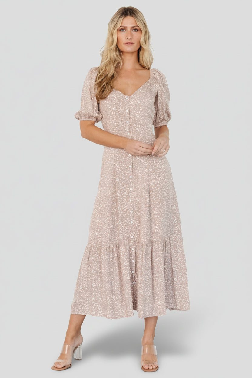 Front view of a beige floral maxi dress with wide scoop neckline, button-front, puffed sleeves and flowing tiered skirt, shown on a model.