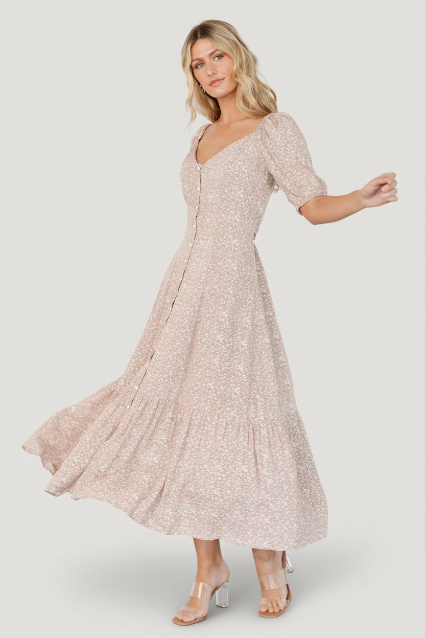 Close-up of the button-front and wide scoop neckline on a beige floral maxi dress, showing fabric texture and partially lined construction.