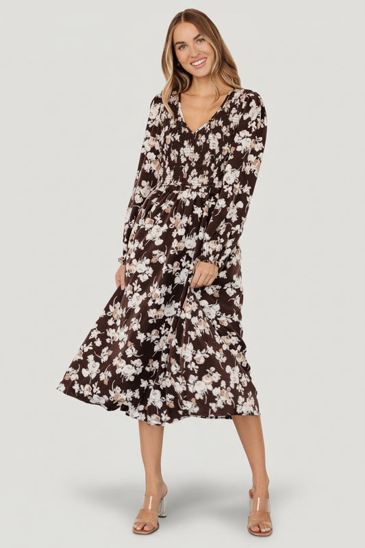 Front view of brown floral smocked midi dress with V-neck, smocked bodice, puffed sleeves, elastic ruffle cuffs, and hidden side pockets.
