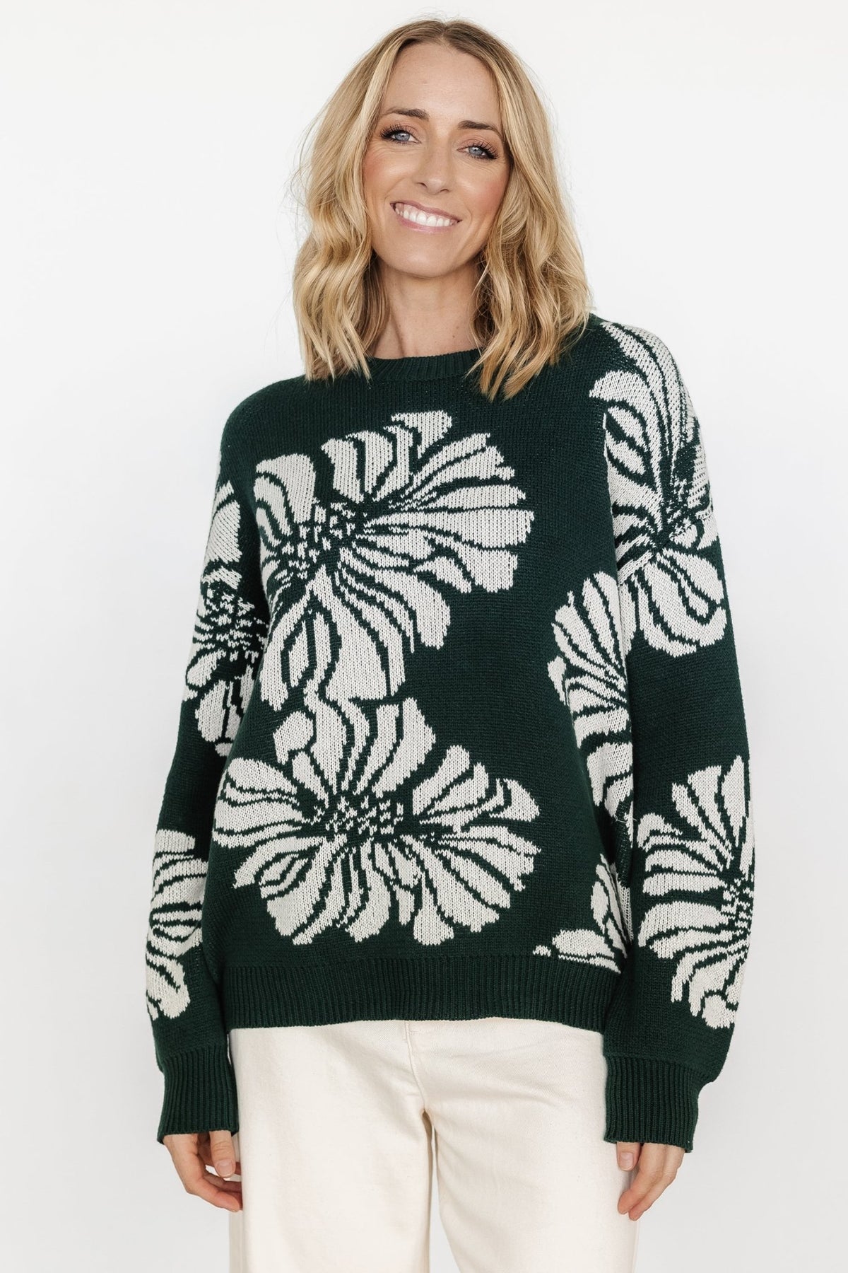 Front view of Maude oversized sweater in deep green with large off-white floral pattern, round neckline and wide ribbed hem for a relaxed fit.