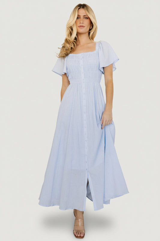 Light blue McKay maxi dress on model showing ruffled square neckline, smocked bodice and flutter sleeves, front view.