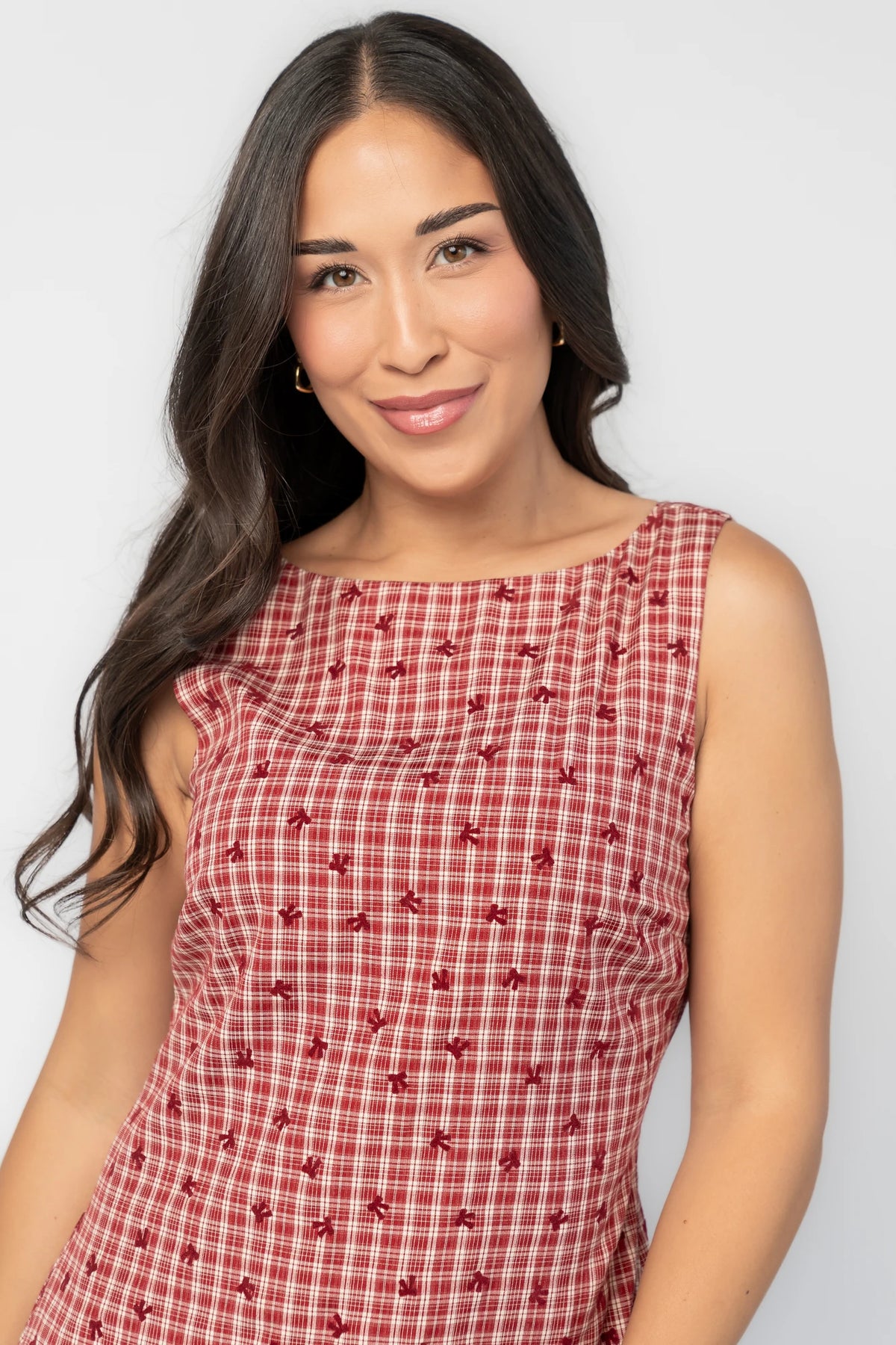McQueen Short Dress in Red Gingham with bow details, sleeveless fitted bodice, drop waist, and ruffled short skirt.