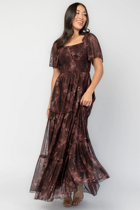 Meya Mesh Maxi Dress in Dark Mahogany Print with abstract florals, smocked bodice, flutter sleeves, and tiered skirt.