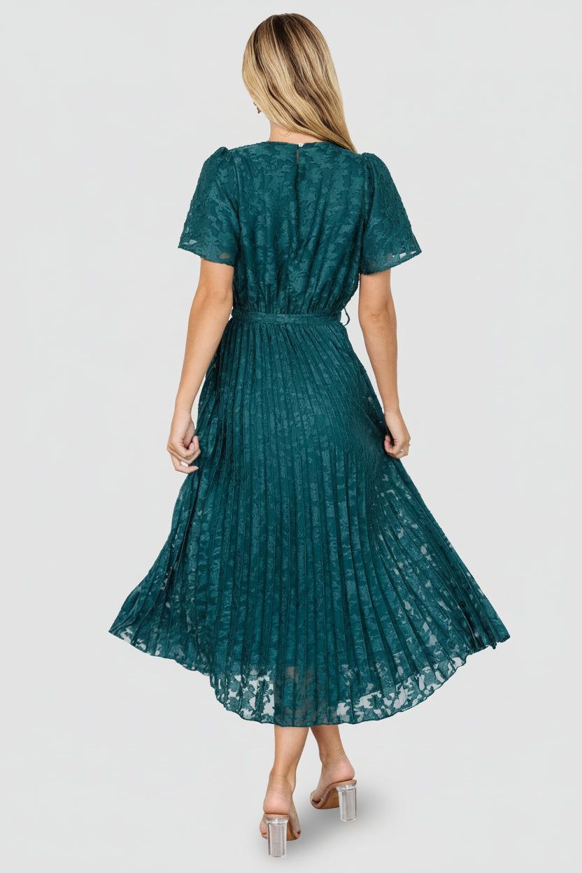 Full-length image of emerald pleated midi dress on model, emphasizing ankle-length skirt and graceful movement in motion.