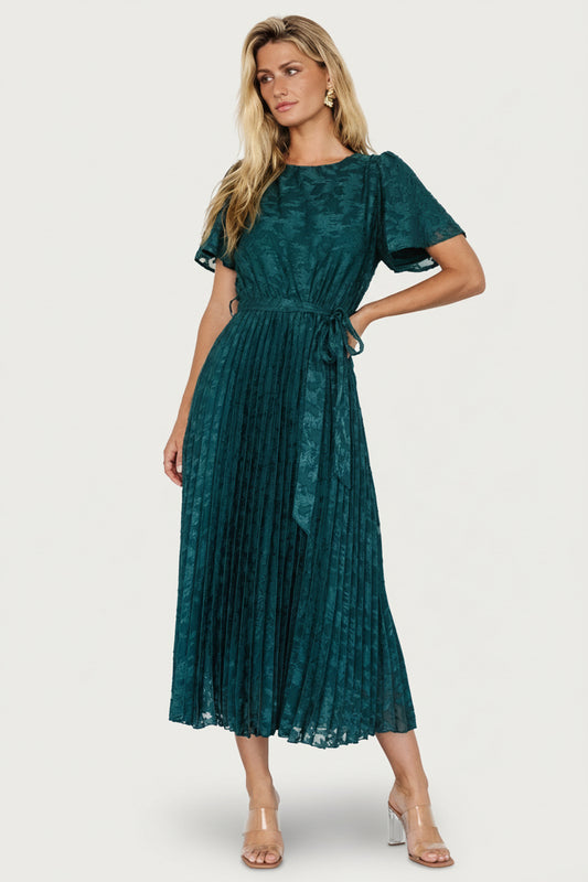 Three-quarter view of emerald chiffon midi dress showing floral applique detail on bodice, elastic waist, and flowing pleated skirt.