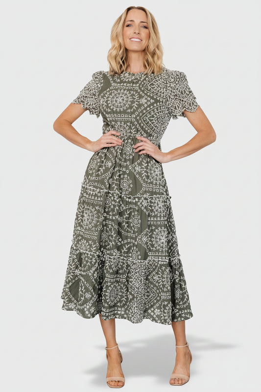 Front view of Mirabel Eyelet Midi Dress in olive and white showing embroidered eyelet, ruffle neckline, and tiered skirt.