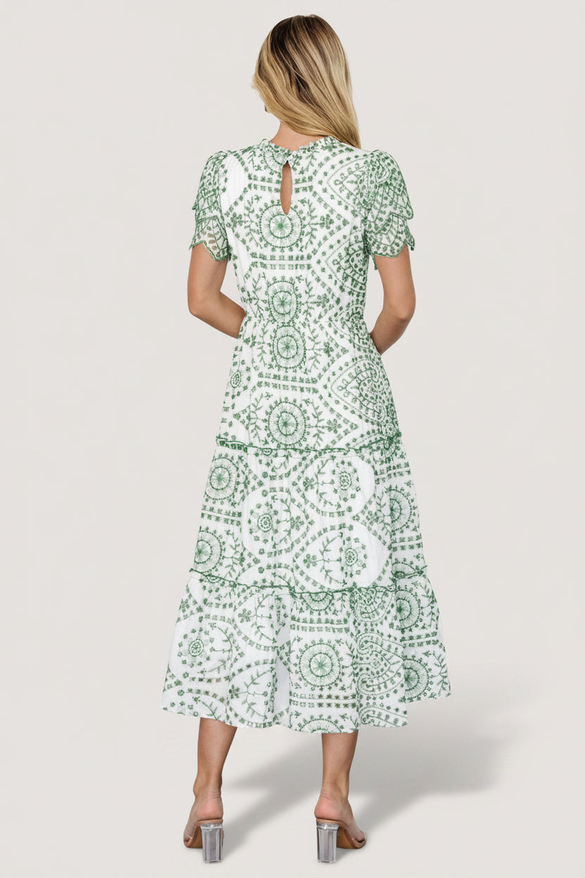 Side view revealing hidden side pocket and tiered midi skirt with ruffle trims, on white cotton embroidered fabric.