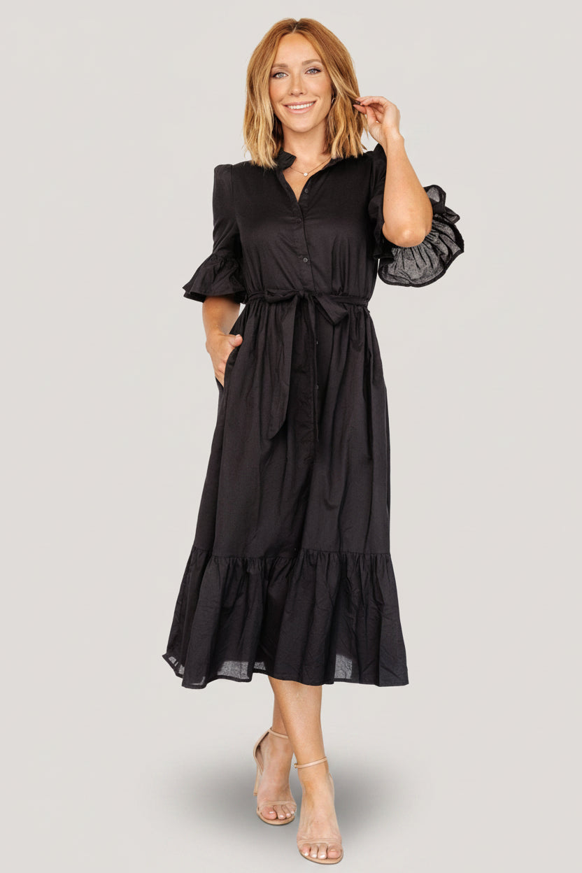 Back view of the black Mirielle midi dress showing the skirt silhouette, gathered tier, and length hitting mid-calf.