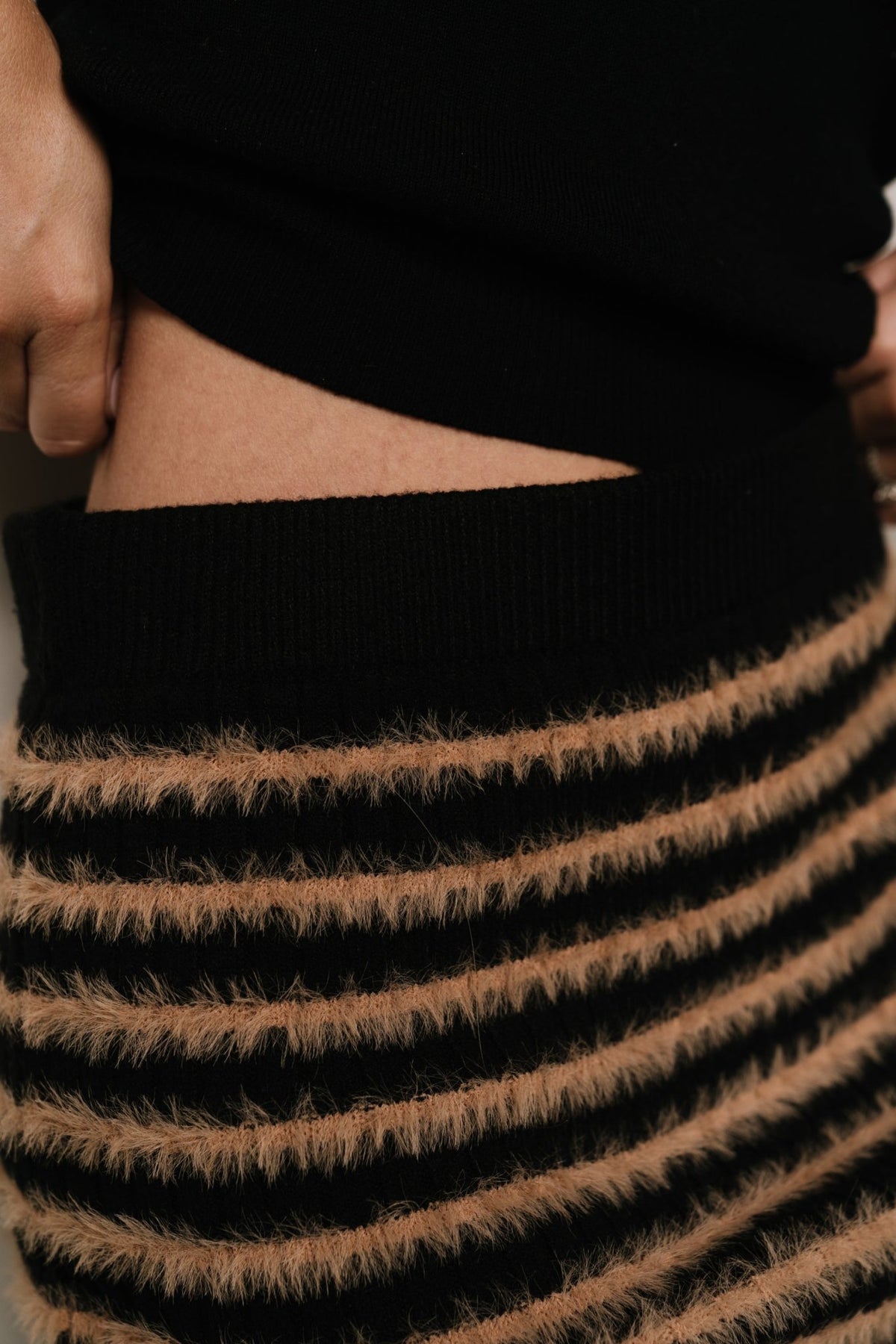 Mitzi ribbed midi skirt in black and camel stripes shown on model, highlighting midi length and fitted hip silhouette.