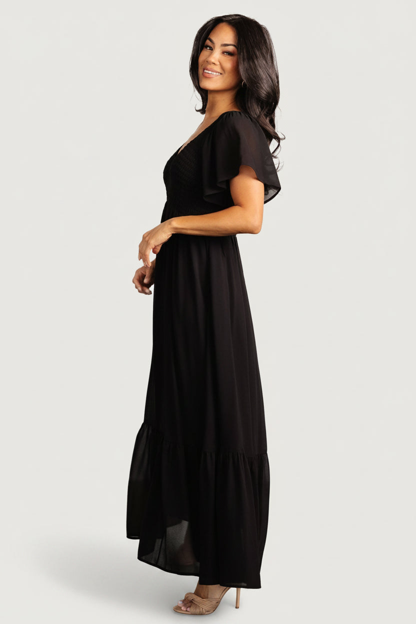 Back and hem detail of the Monica Smocked Dress in black showing single bottom tier and lined skirt for coverage.
