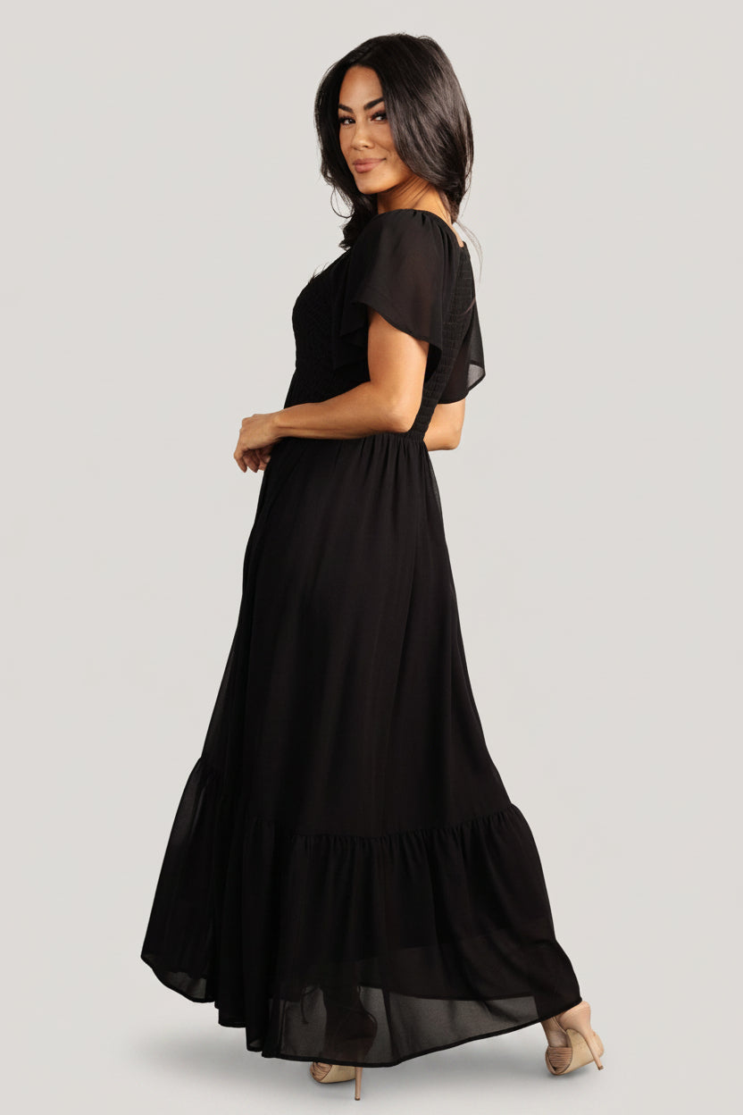 Sleeve detail of Monica dress showing flutter sleeve and smocked shoulder detail in lightweight black chiffon fabric.