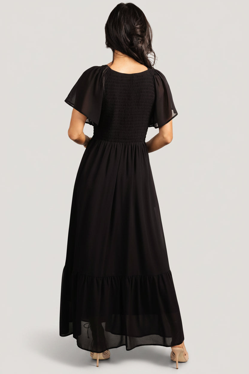Side view highlighting hidden pockets and fluid movement of the Monica Smocked Maxi Dress in black chiffon.