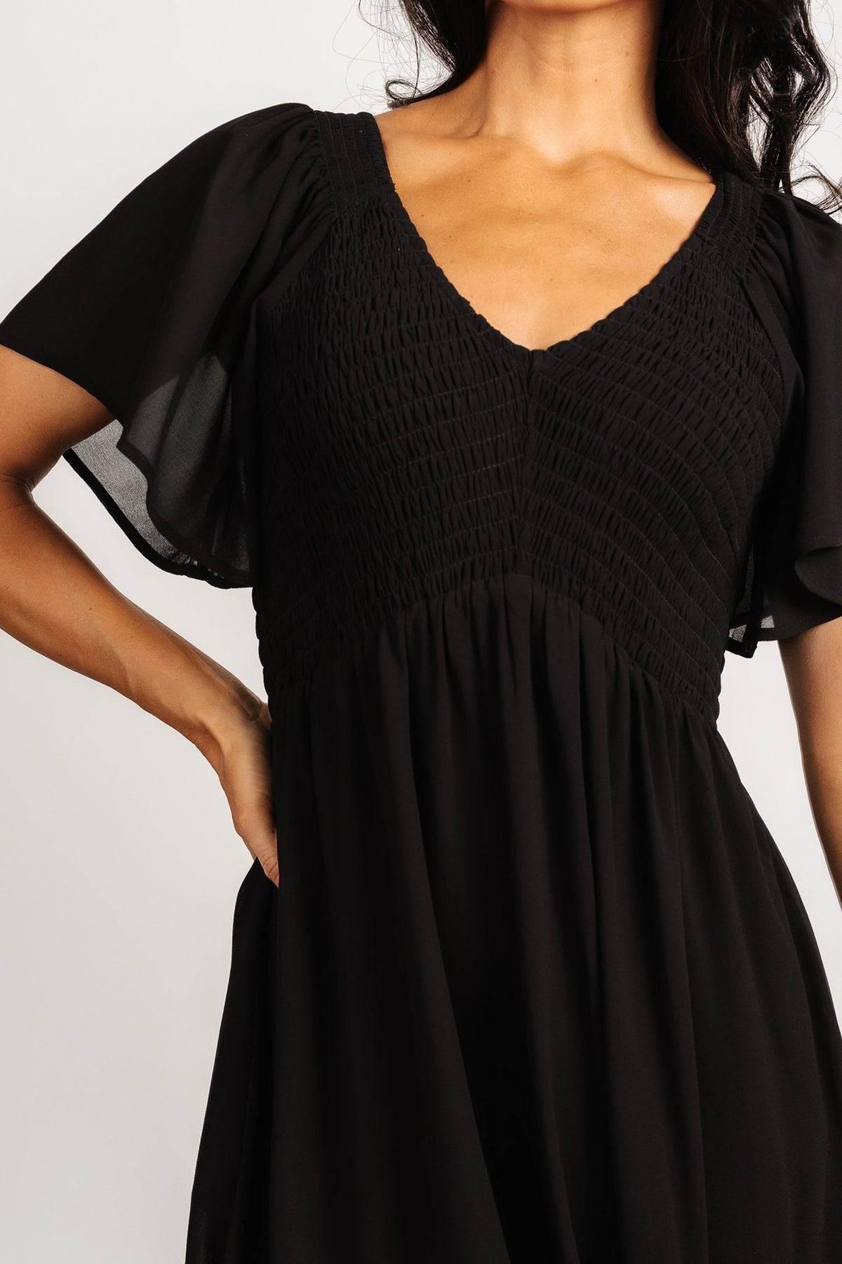 Model wearing Monica Smocked Dress in black, showing full length, subtle tier at hem, and natural drape of chiffon fabric.
