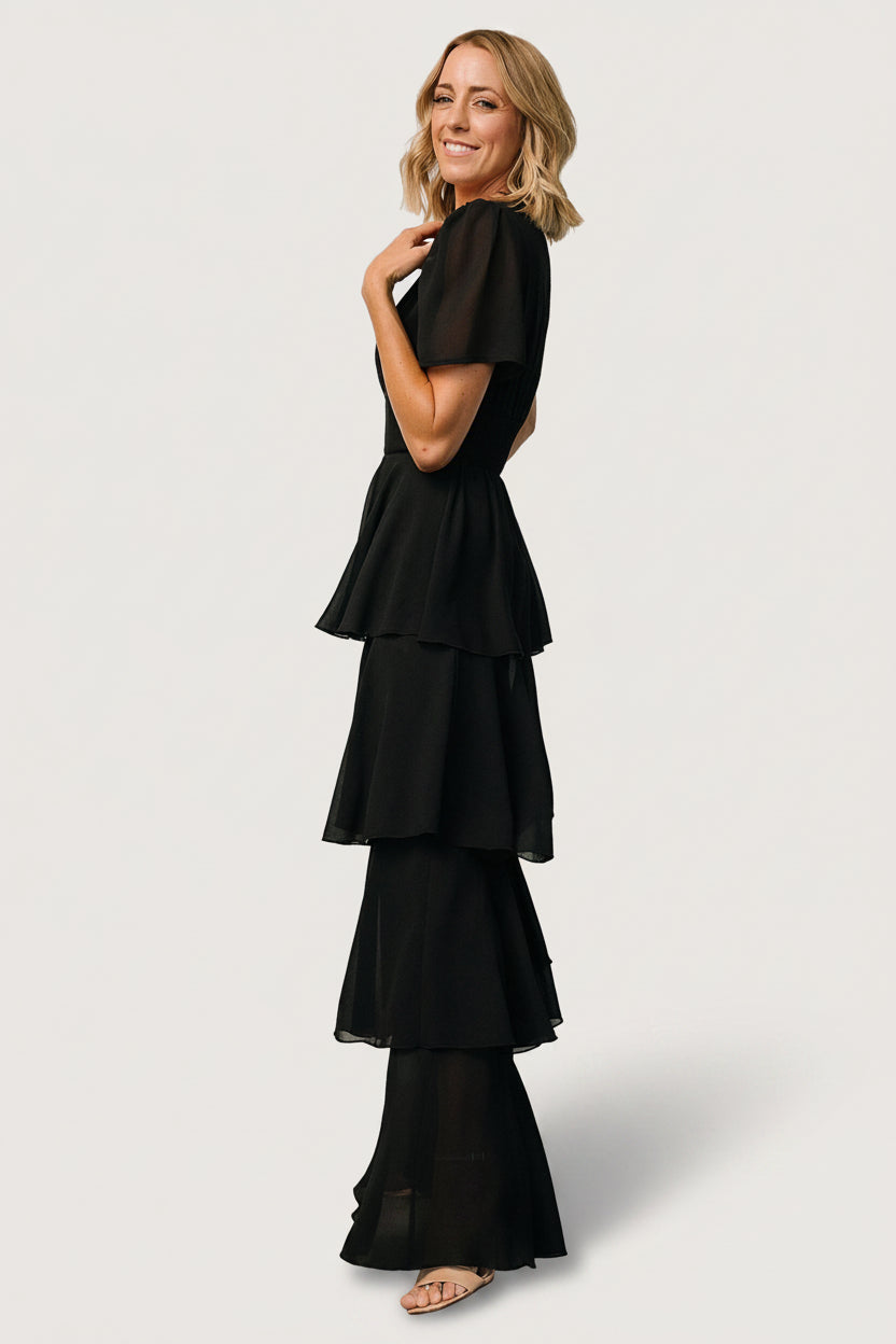 Side view of the black Montaigne ruffle maxi dress emphasizing the cascading, asymmetrical ruffle tiers and full-length silhouette.