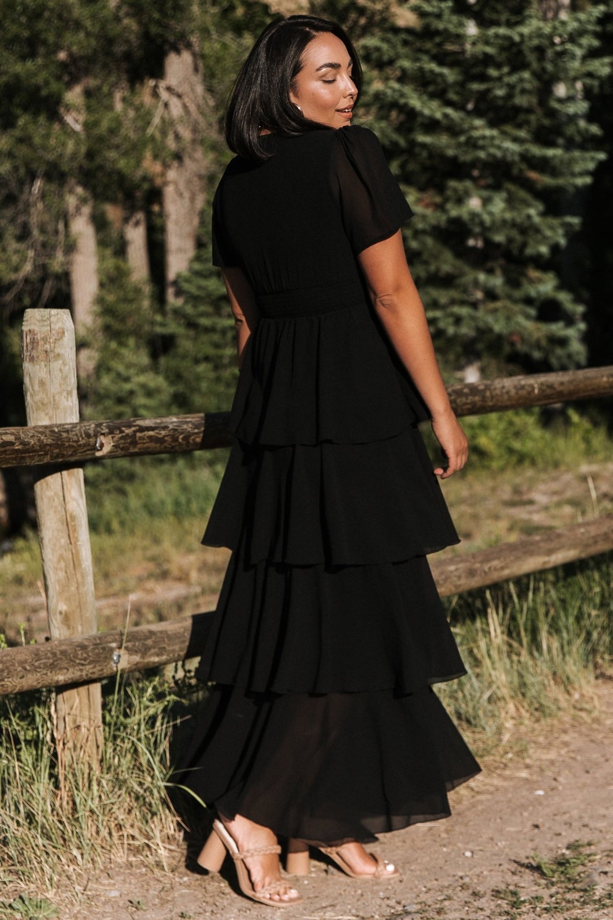 Model wearing the black Montaigne ruffle maxi dress walking to show skirt movement, ruffle tiers, and natural drape of the fabric.