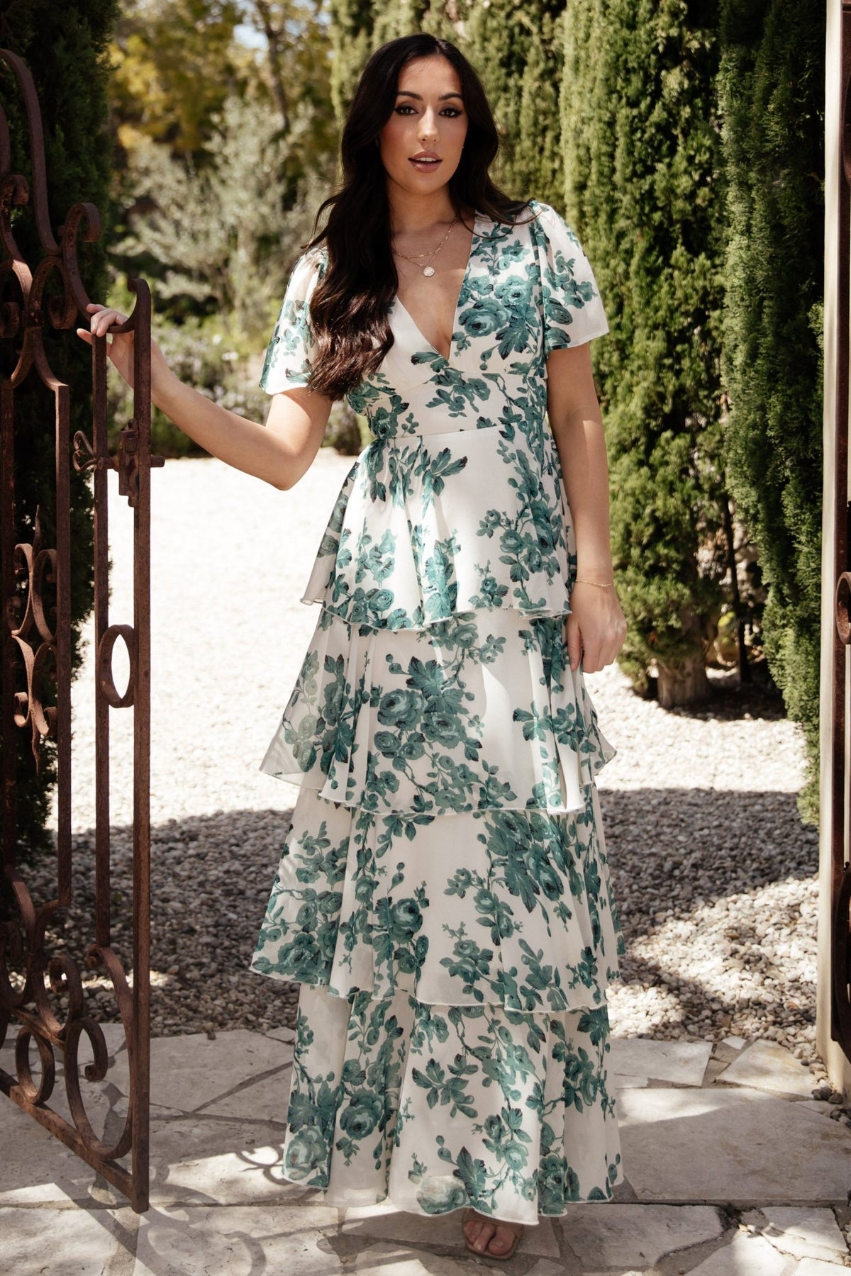 Model movement shot of the ivory and green floral maxi, emphasizing flowing skirt and asymmetric ruffle cascade.