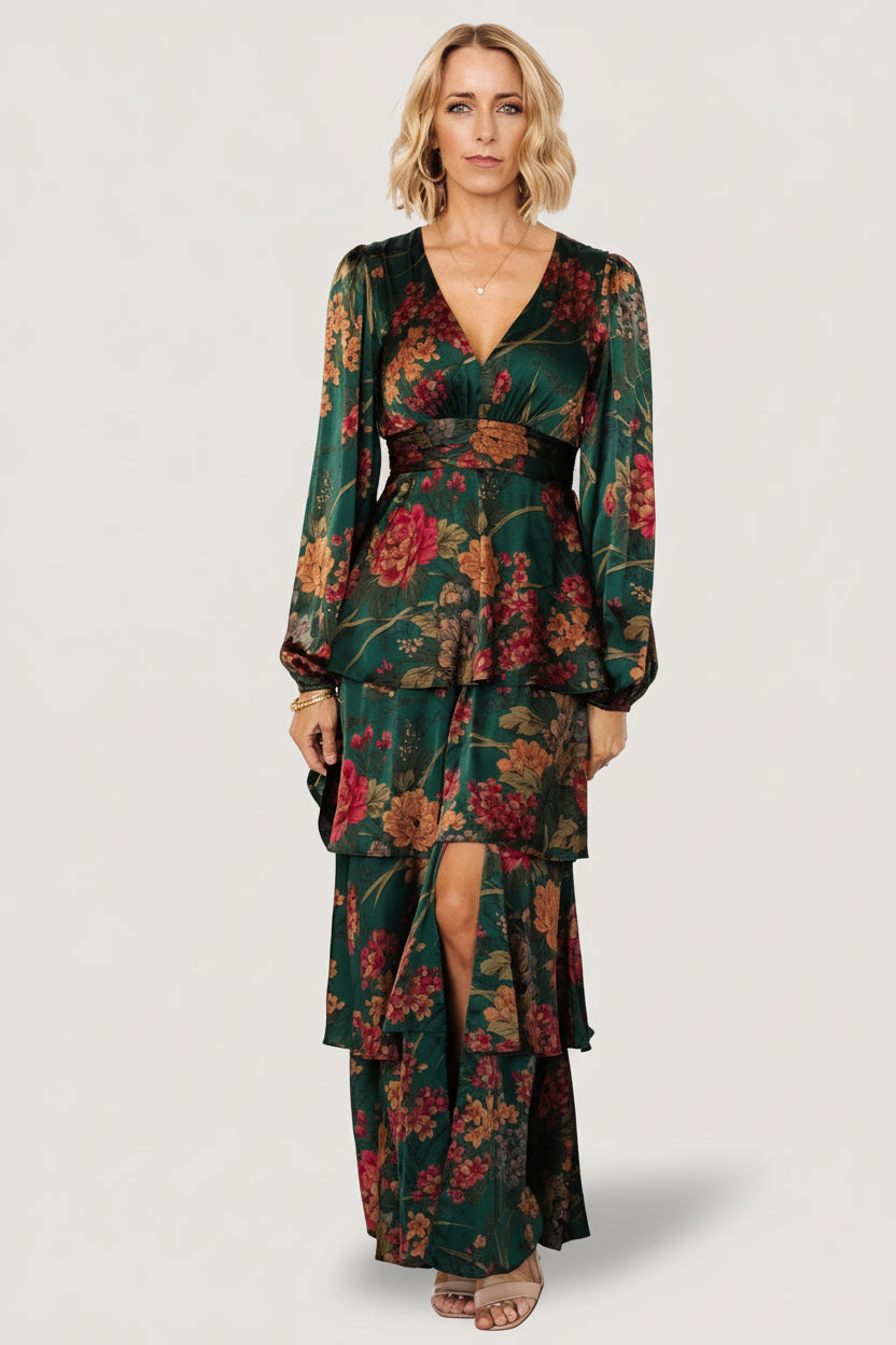 Front view of emerald floral satin maxi dress on model, showing v-neck, short flowy sleeves, and tiered cascading ruffle skirt (full length).