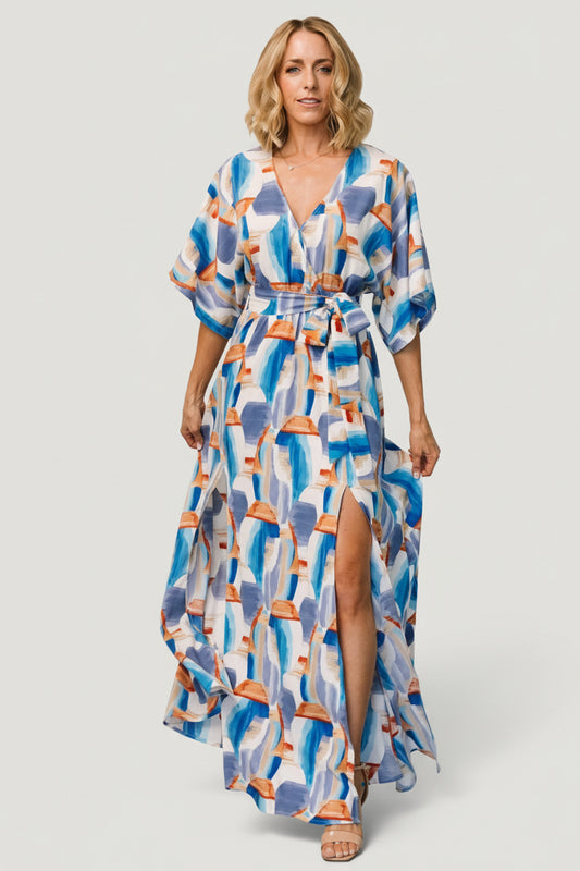 Front view of blue brushstroke-print surplice maxi dress with removable sash, wide cape sleeves, and high side slits for movement.