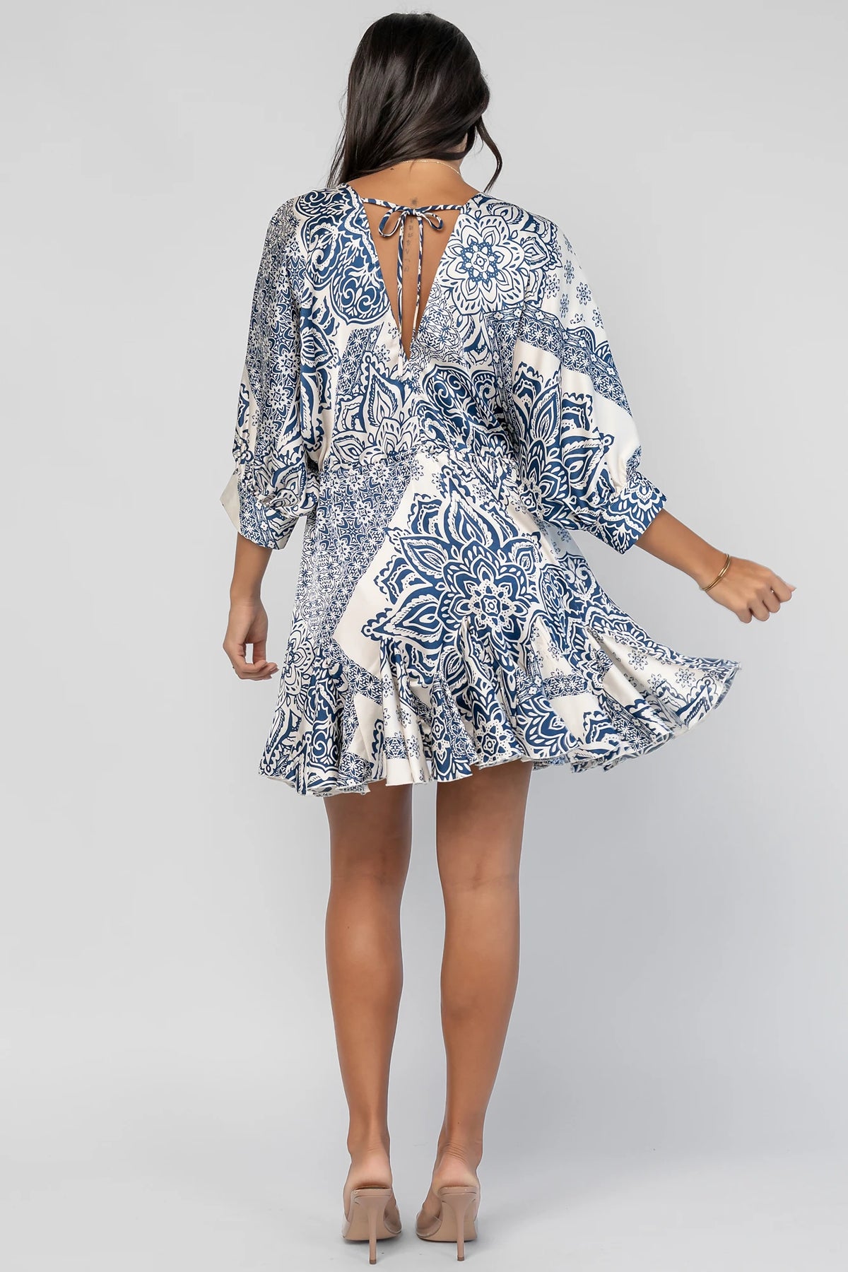 Morwen Short Dress in Navy Print with a V-neckline front and back, batwing sleeves, and a ruffled paneled skirt.