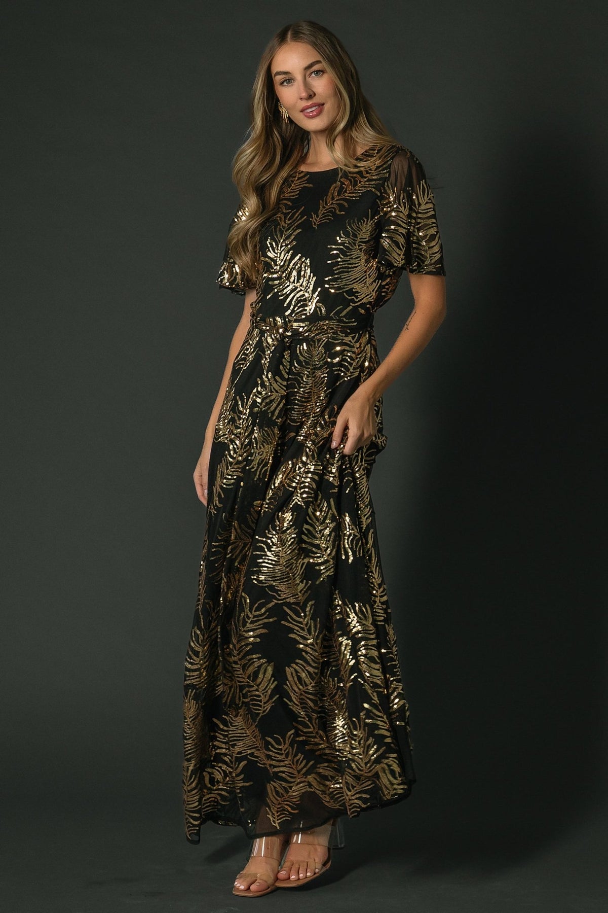 Close-up of gold sequin leaf pattern on black fabric, showing shimmer, sequin texture, and delicate applique across the bodice.