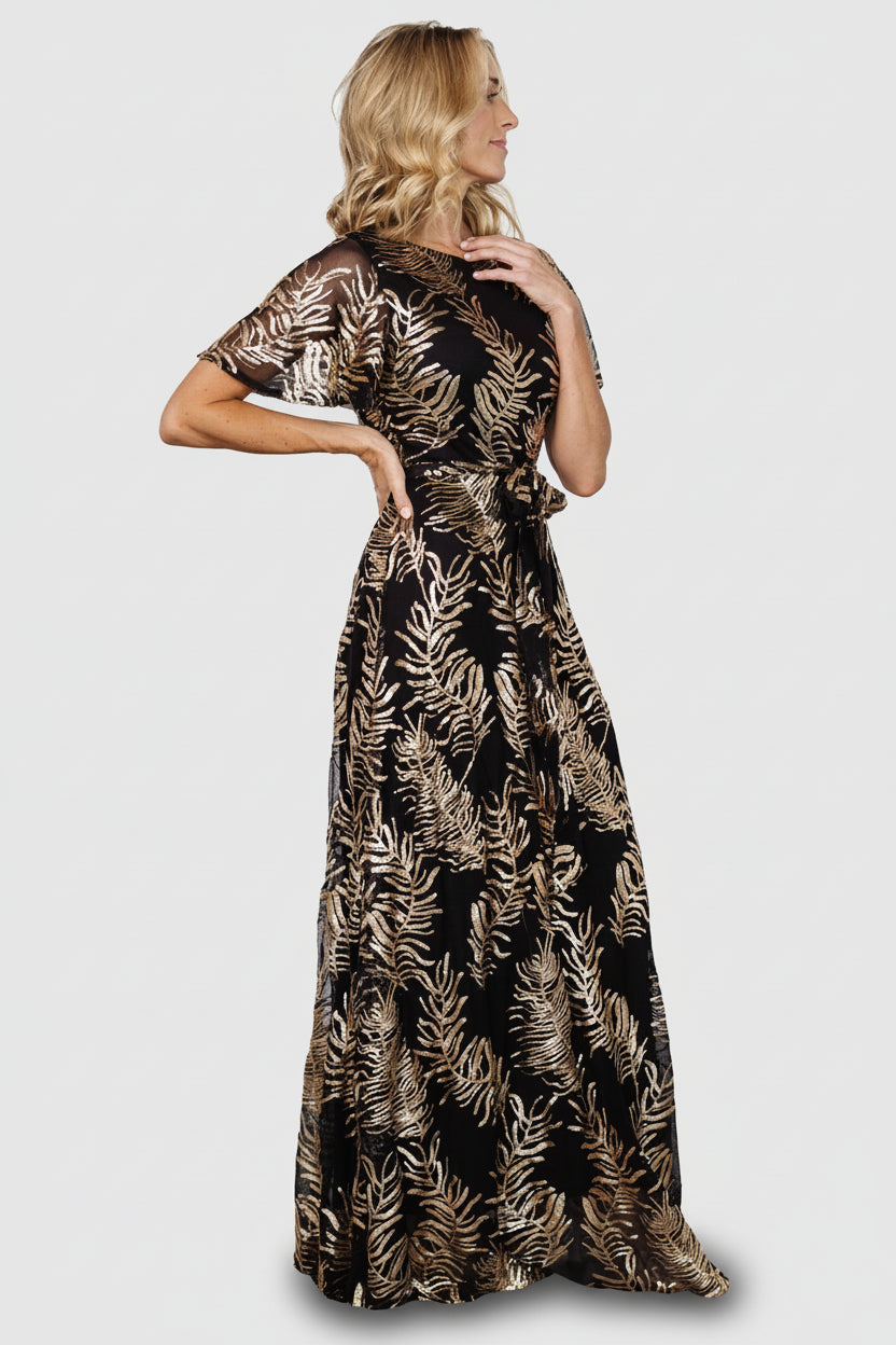 Side profile of maxi-length skirt with full sequin coverage, lined body, and sheer short sleeves for light, elegant movement.