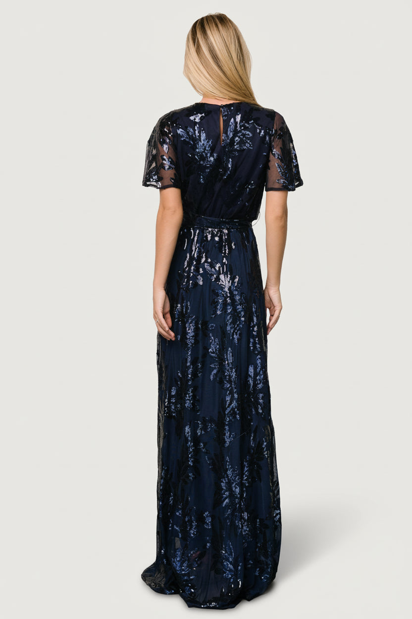 Back view of the navy sequin maxi showing keyhole and single-button closure, sequin placement, and how the sash ties at the waist.