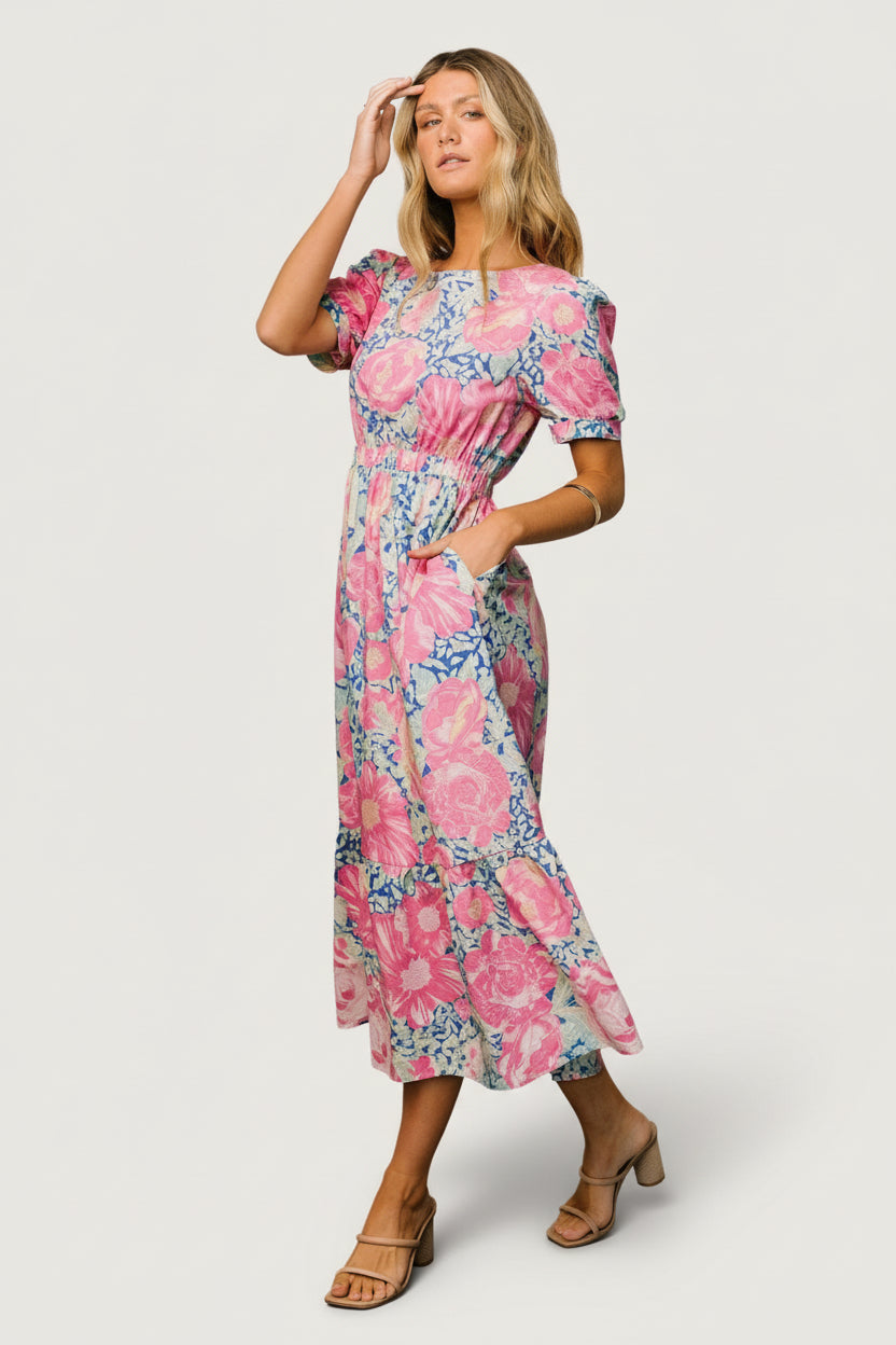 Studio close-up showing the blue and pink floral print, fabric texture, and partial lining detail on the tiered midi dress.